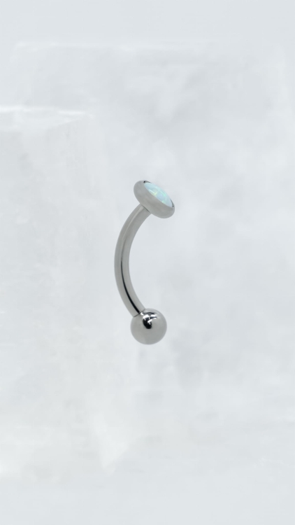 Kolczyk do piercingu rook – tytanowy banan z białym opalem | widok z boku Profil kolczyka do rook z tytanu. Widok z boku podkreśla kształt banana, zakrzywienie pręta oraz sposób osadzenia białego opalu.