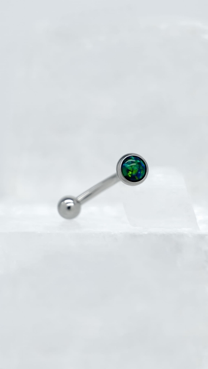 Kolczyk do rook z zielonym opalem – tytan implant-grade | detal Zbliżenie na detal kolczyka do piercingu rook. Precyzyjne wykończenie tytanu oraz intensywny kolor zielonego opalu podkreślają jakość i estetykę biżuterii.